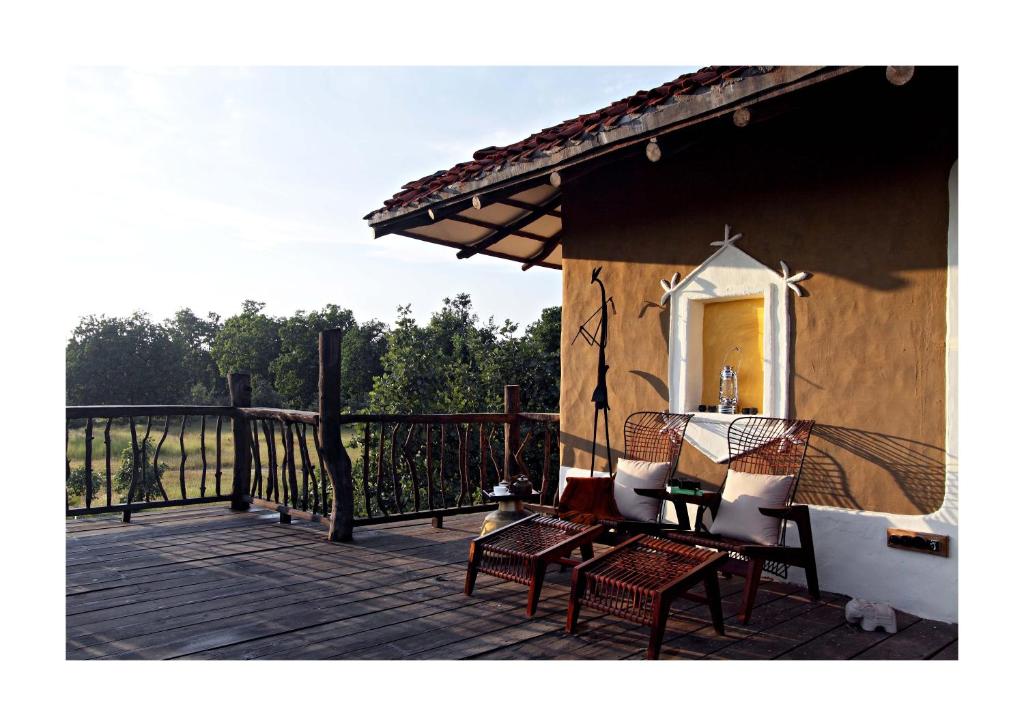 a porch with chairs and a table on a deck at Samode Safari Lodge in Parāsi
