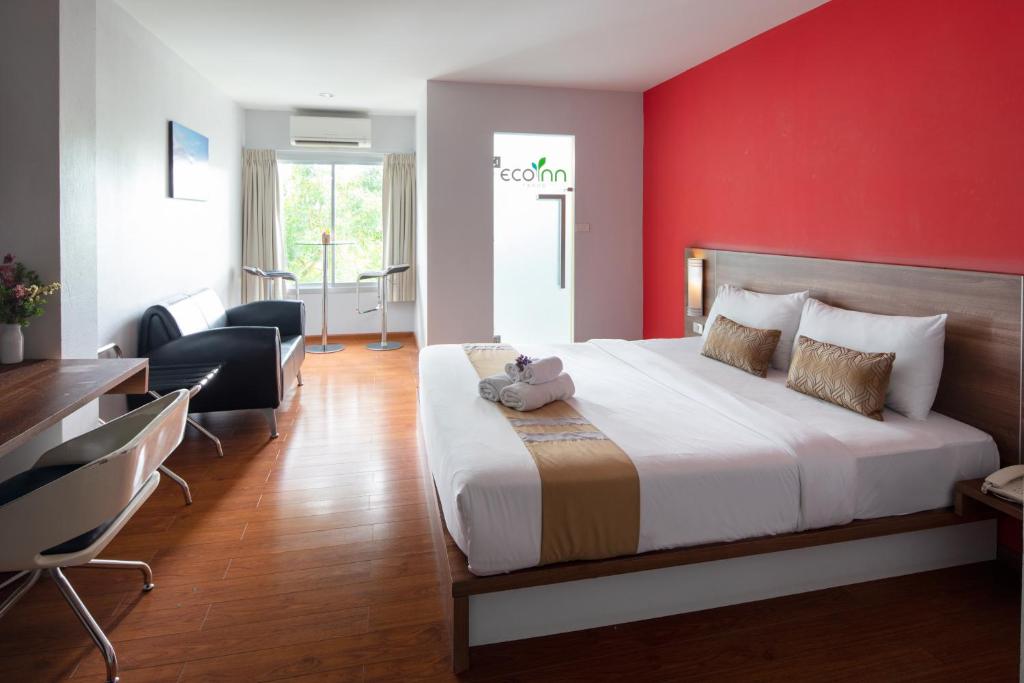 a bedroom with a large bed with a red wall at Eco Inn Prime Trang in Trang