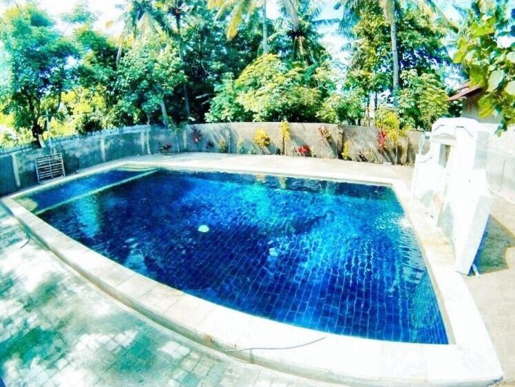 a swimming pool with blue water in a backyard at Santai Bungalow in Gili Trawangan