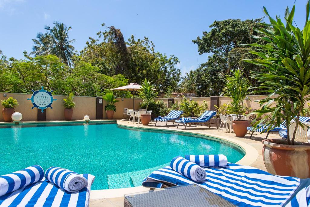 uma piscina com toalhas e cadeiras listradas em azul e branco em Bliss Resort em Nyali