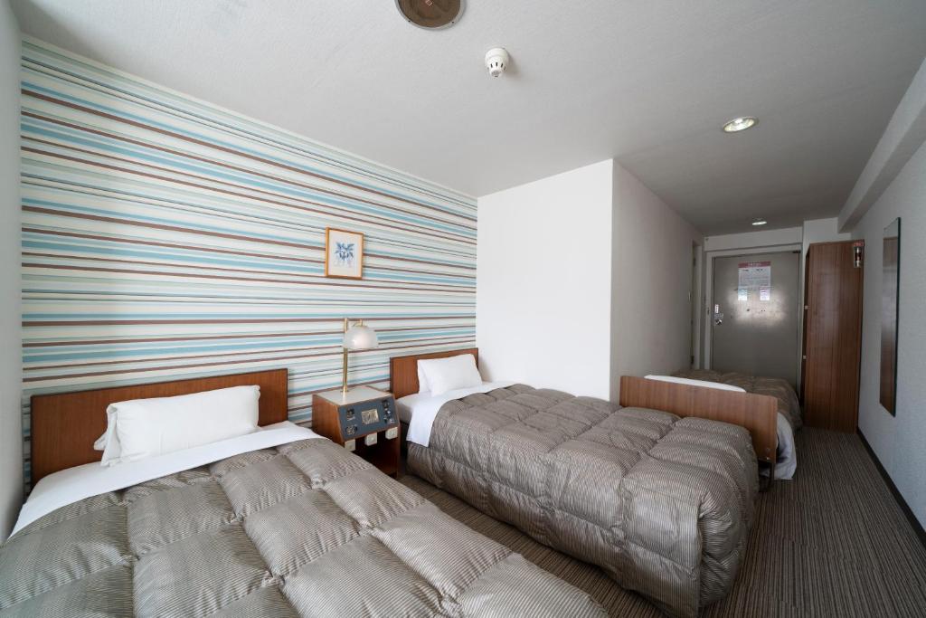 a bedroom with two beds and a striped wall at Hotel Econo Higashi Kanazawa in Kanazawa