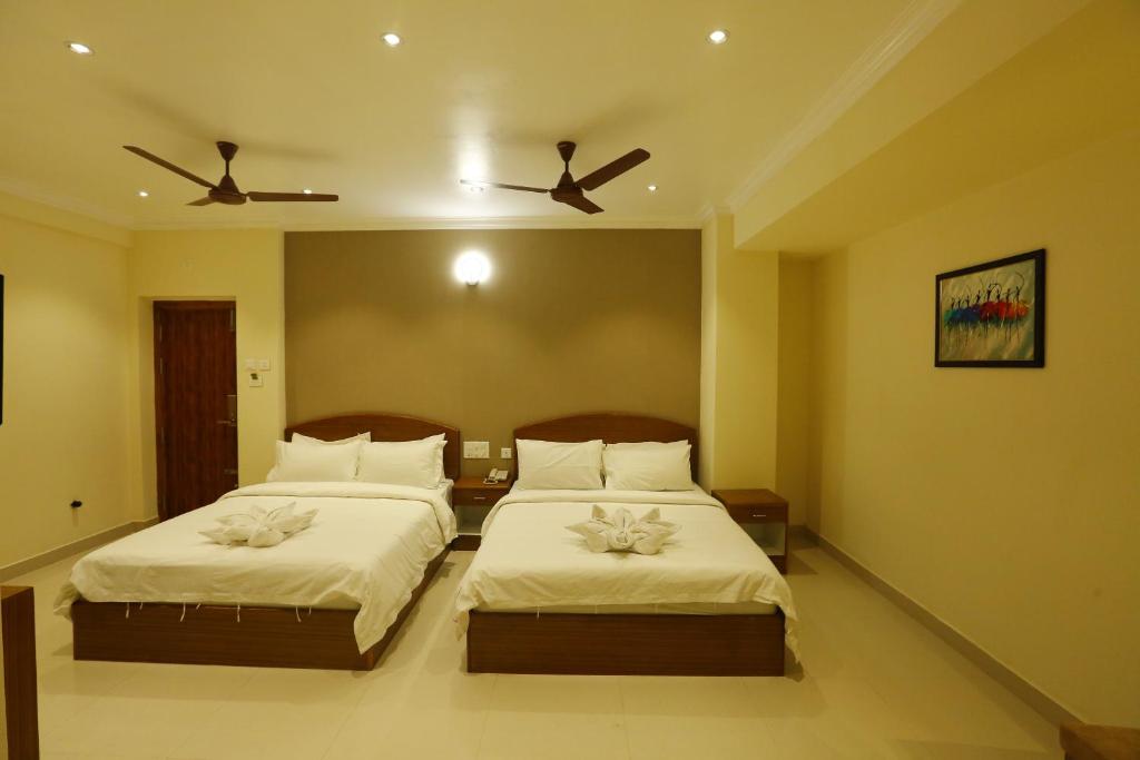 een slaapkamer met 2 bedden en 2 plafondventilatoren bij Nitheesh Residency in Kanchipuram