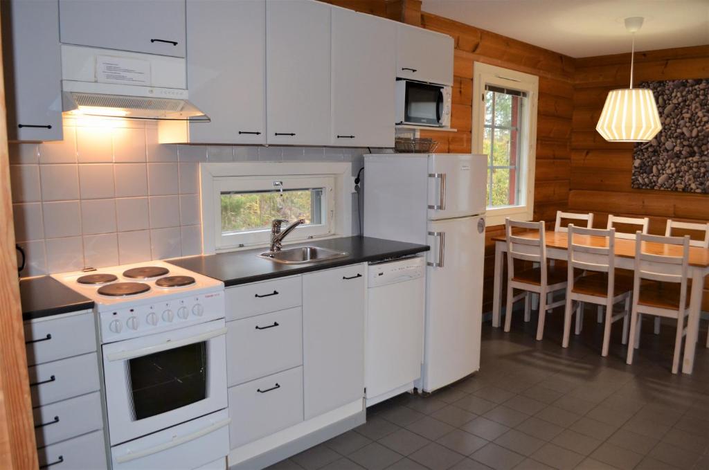 a kitchen with white appliances and a dining room at Rauhalahti Holiday Homes in Kuopio