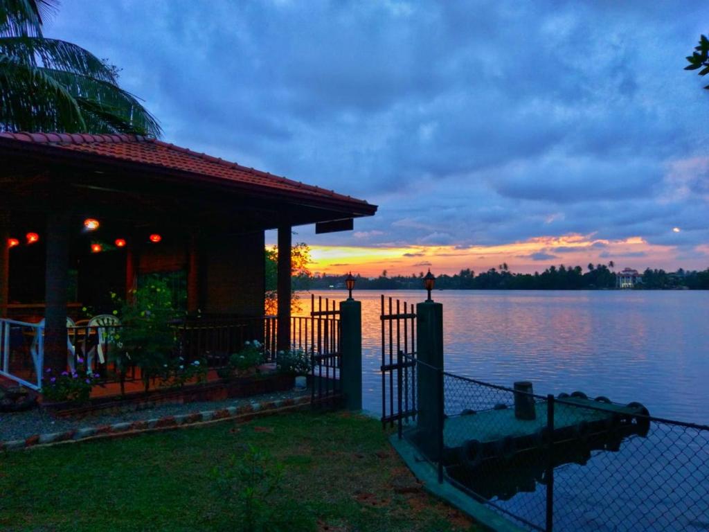 a house with a fence in front of a lake at Selavi Resort Bentota in Bentota