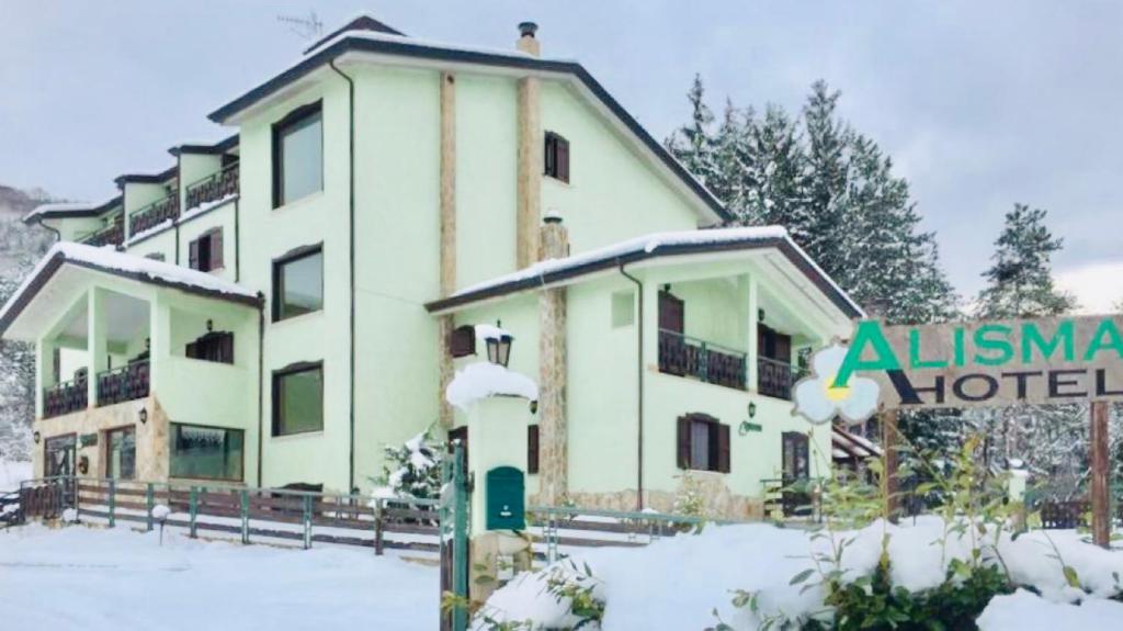 a hotel in the snow with a sign in front of it at Hotel Alisma in Alfedena