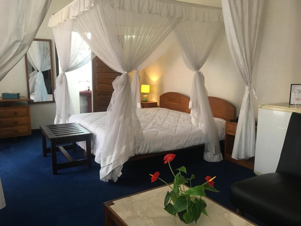 a bedroom with a bed with white drapes at Ivotel in Antananarivo