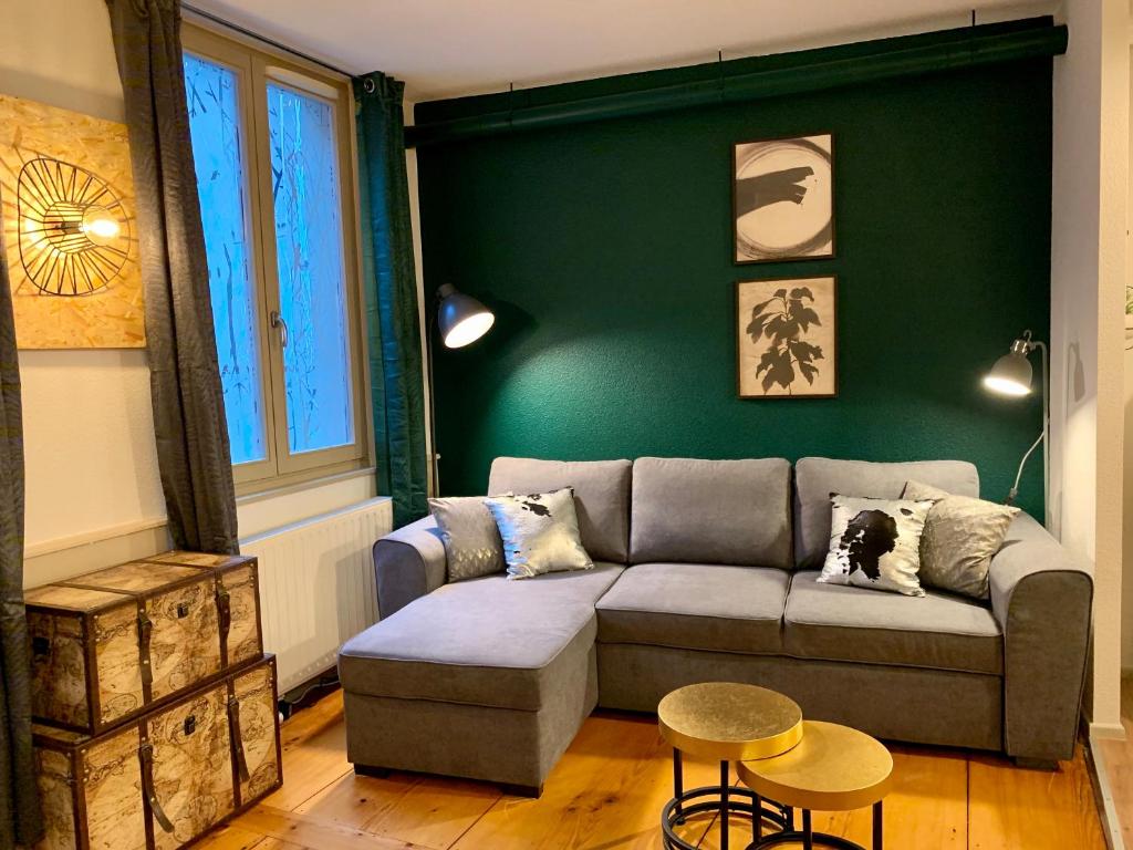 a living room with a couch and a green wall at Appartements des 2 Têtes in Colmar