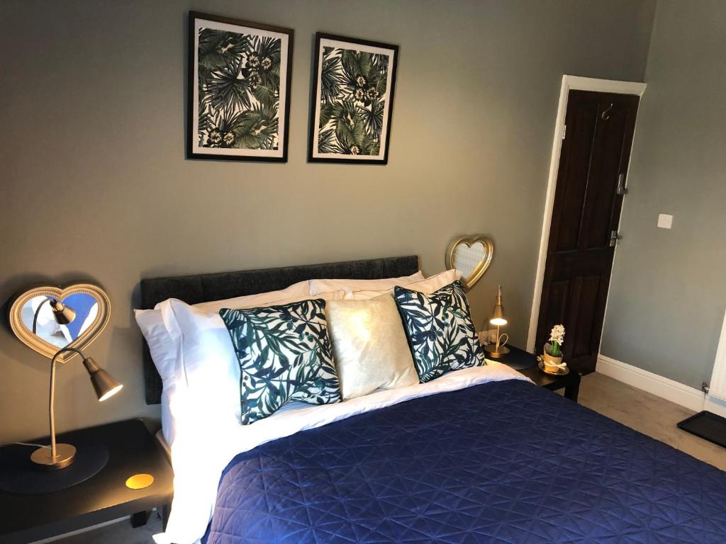 a bedroom with a blue bed and three pictures on the wall at 3. Stylish Private Double Room Near Manchester City Centre in Manchester