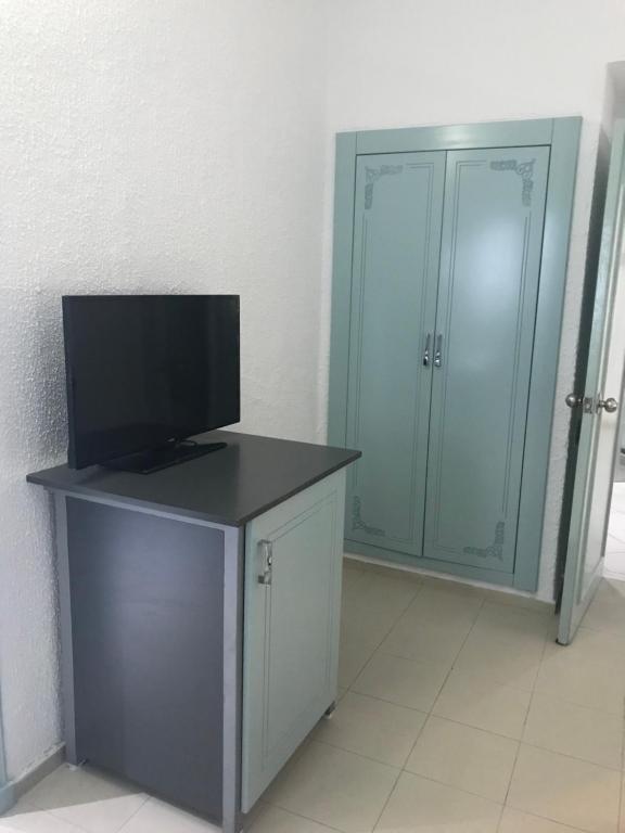 a room with a television on a desk with a closet at Hotel Khella in Hammamet