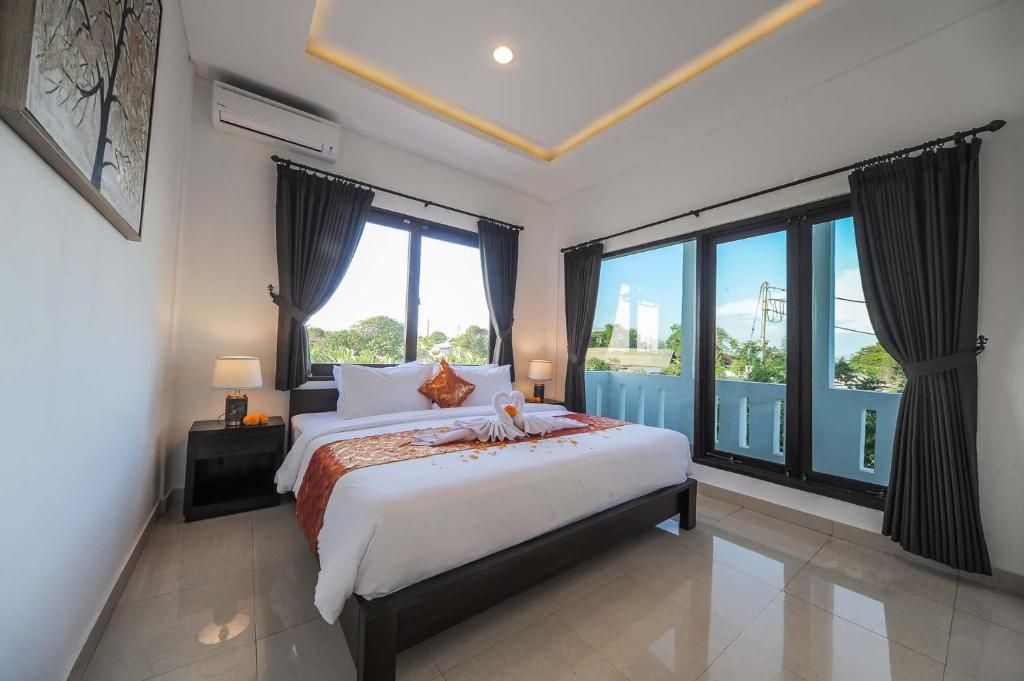 a bedroom with a large bed and large windows at Villa Rindik Sanur in Sanur
