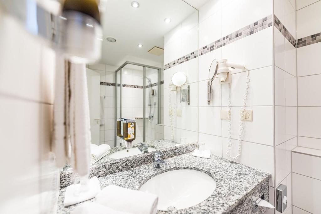 a bathroom with a sink and a large mirror at Hotel am Schloß Apolda in Apolda