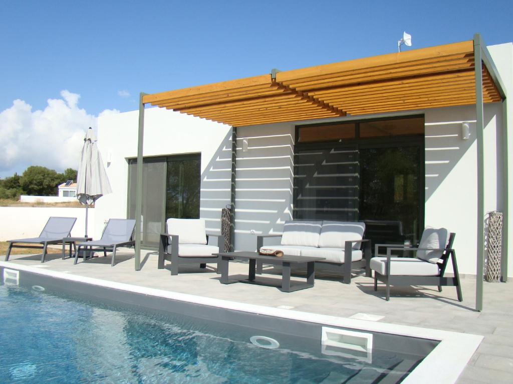 a group of chairs and a swimming pool next to a house at Villa Esther in Kefallonia