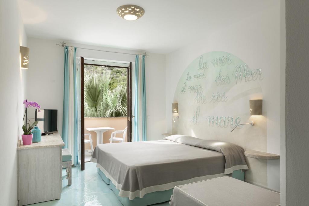 una camera da letto con un letto con scrittura sul muro di Hotel Corallaro a Santa Teresa di Gallura