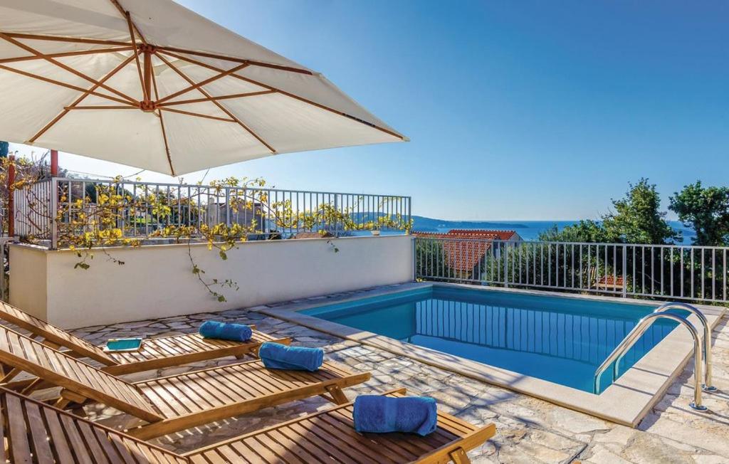 a swimming pool with an umbrella and two chairs and a table at Villa Maestral in Brsečine