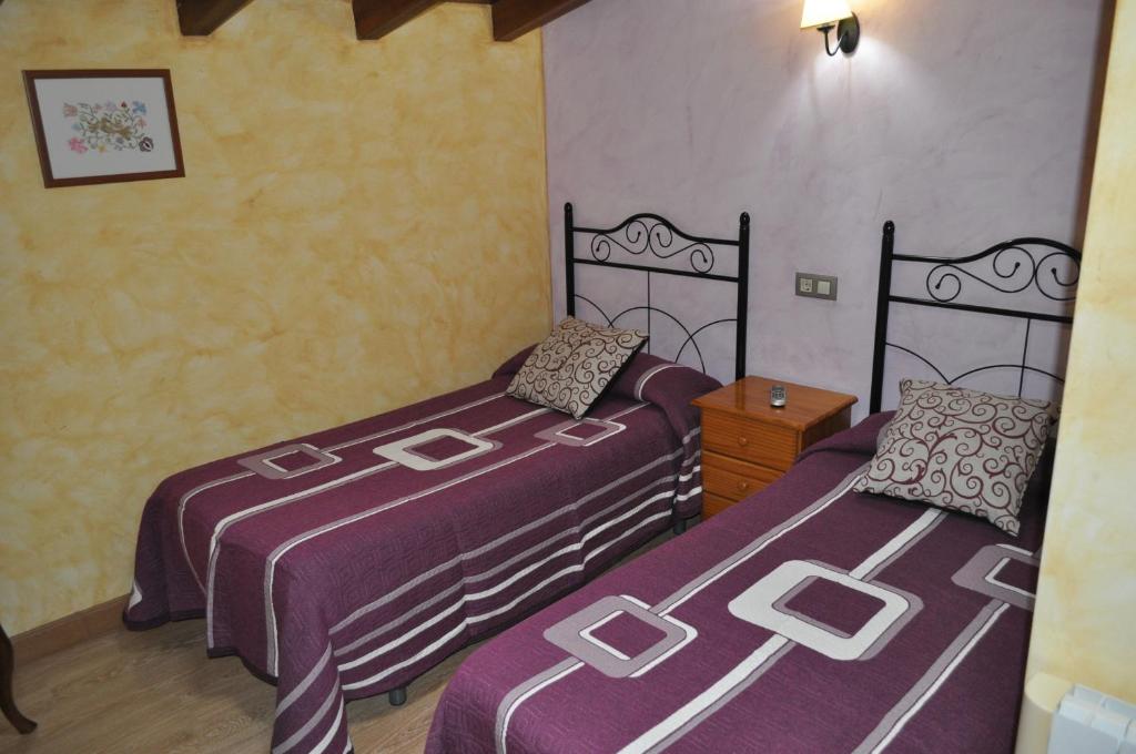 two beds in a room with purple sheets at Casa Rural Carpintero in Los Santos