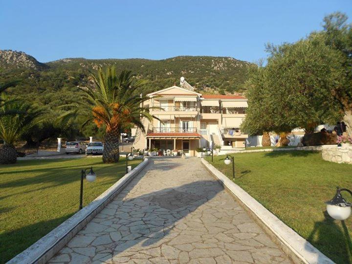 a walkway in front of a building with palm trees at Leonidas Studios in Sami