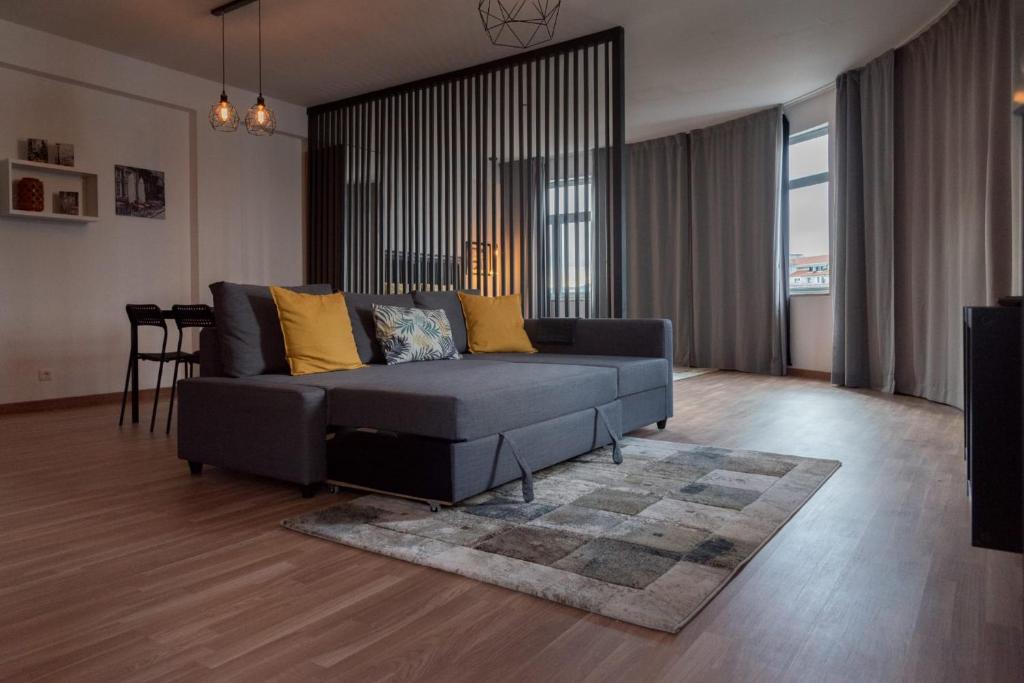 sala de estar con sofá negro y almohadas amarillas en Redondo Loft, en Macedo de Cavaleiros