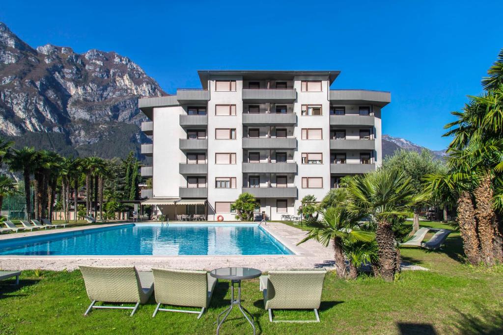 un hôtel avec une piscine et des montagnes en arrière-plan dans l'établissement Residence Monica, à Riva del Garda