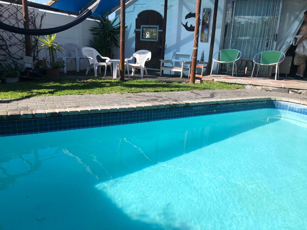 a blue swimming pool with chairs and a table at The Speckled Egg, 4 Promenade Rd, Lakeside, Cape Town in Cape Town