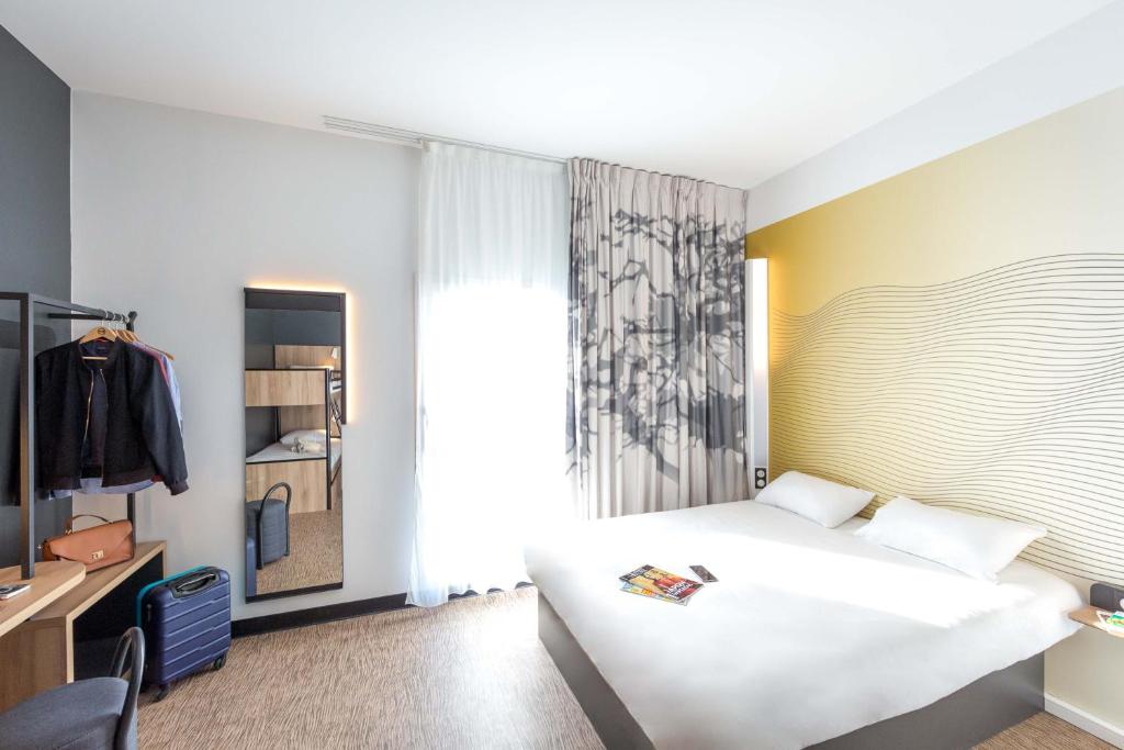 B&B HOTEL Sainte-Maxime Golfe de Saint Tropez في سانت ماكسيم: غرفة نوم بسرير ابيض ونافذة