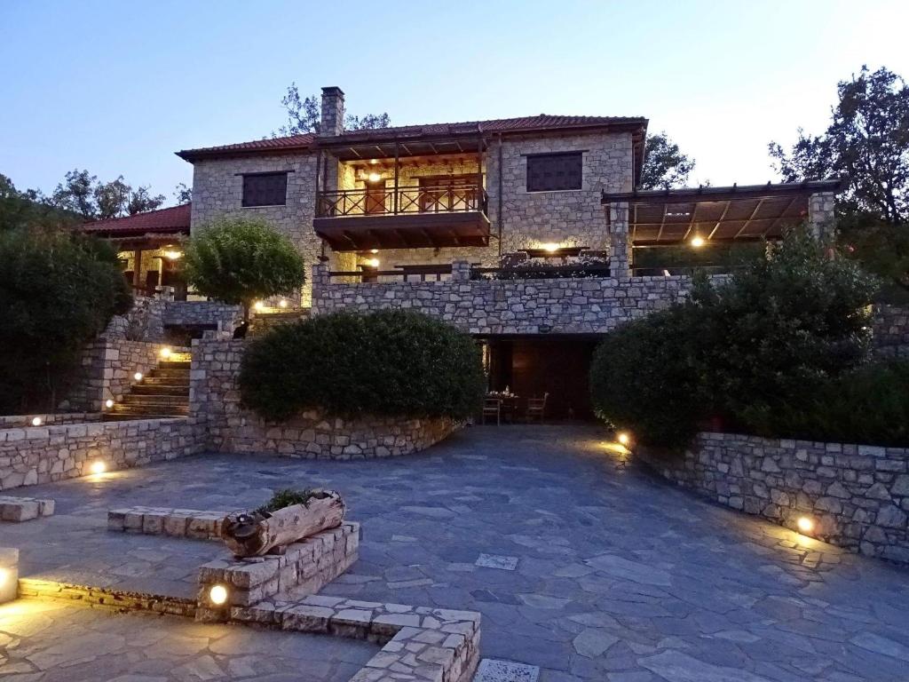 ein großes Steinhaus mit einer Terrasse mit Beleuchtung in der Unterkunft Τείχιο Βίλα - Tihio Villa - Πετρόχτιστη βίλα in Tíkhion