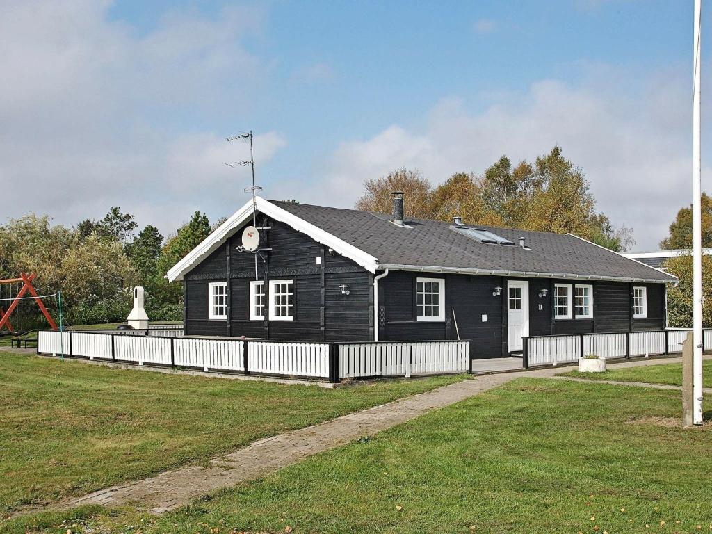 una casa negra con una valla blanca en un patio en 15 person holiday home in Hals, en Hals