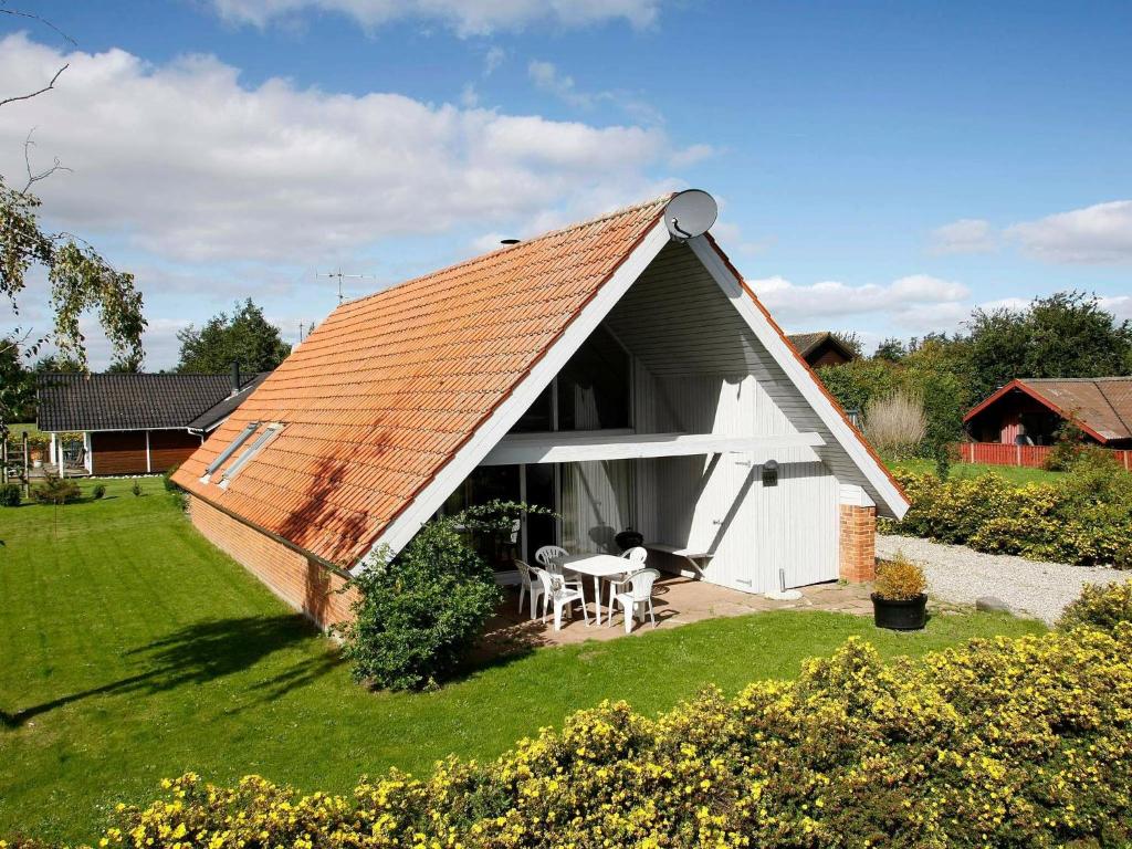 a white cottage with an orange roof on a yard at Five-Bedroom Holiday home in Juelsminde 2 in Sønderby