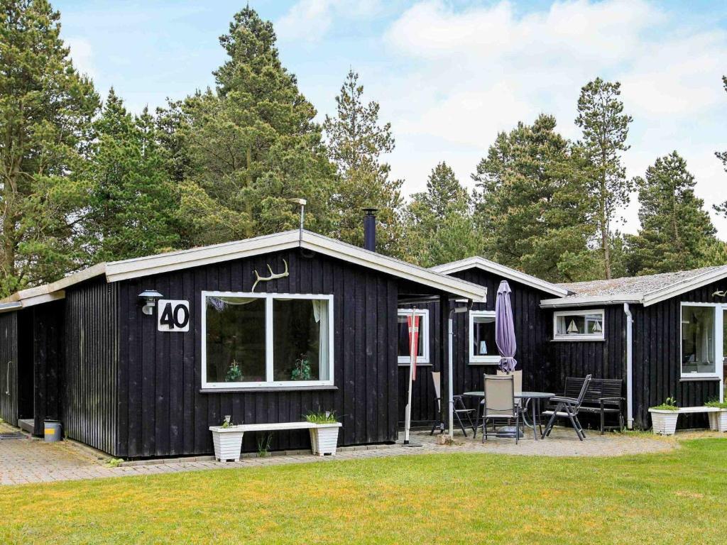 ホにあるThree-Bedroom Holiday home in Blåvand 77のパティオ付きの黒い船積みコンテナキャビン