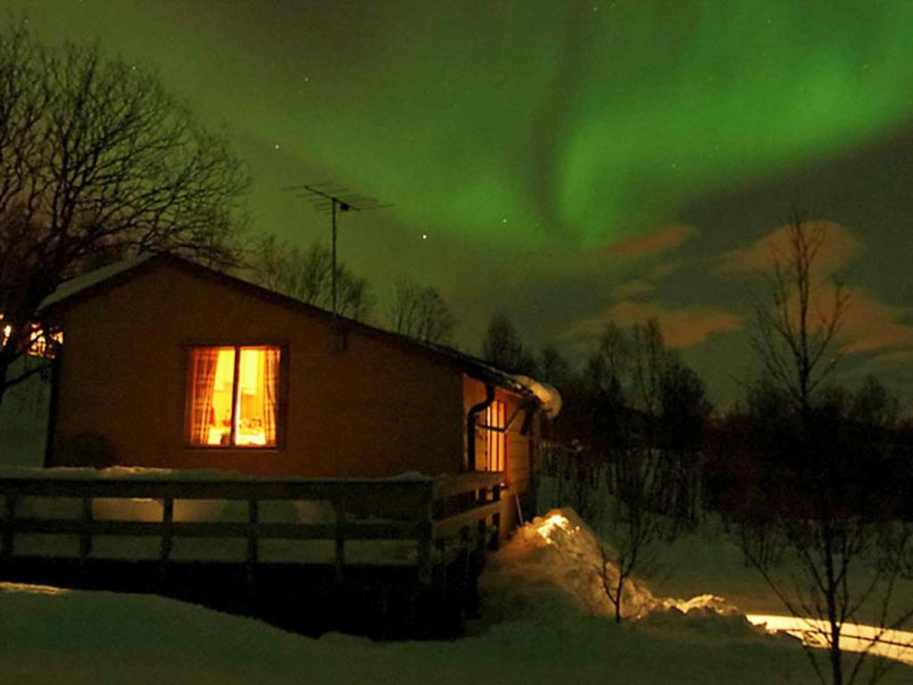 Ein Haus mit grüner Aurora am Himmel in der Unterkunft 5 person holiday home in Straumsbukta in Bakke