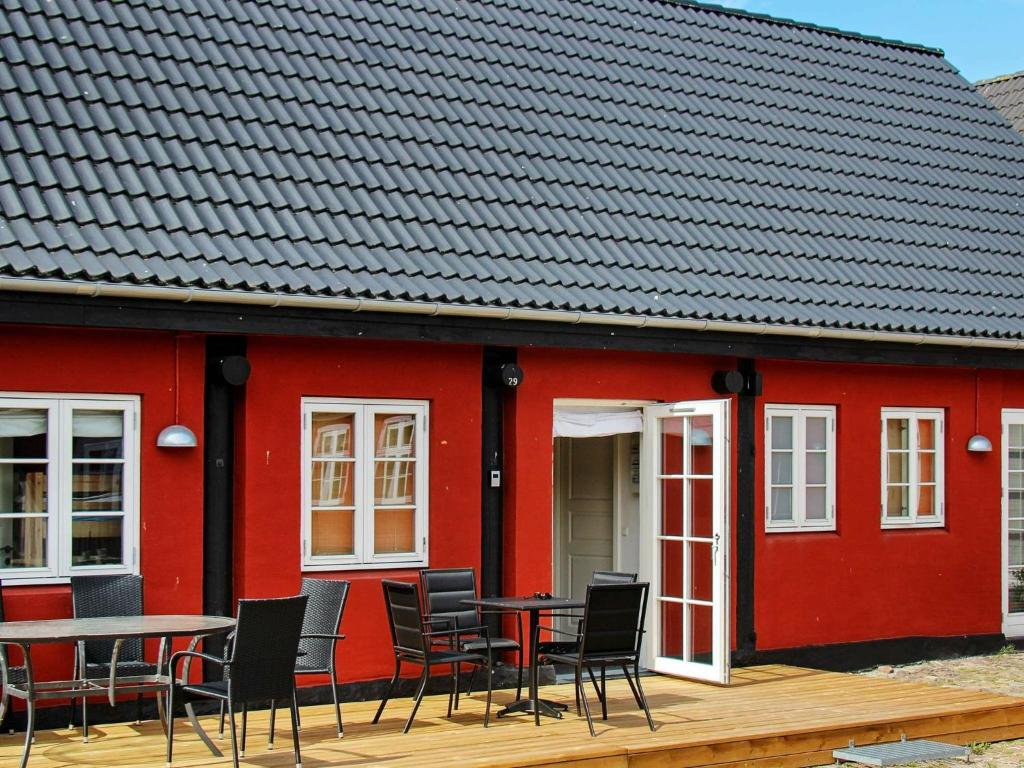 a red building with chairs and tables in front of it at 4 person holiday home in Aakirkeby in Åkirkeby