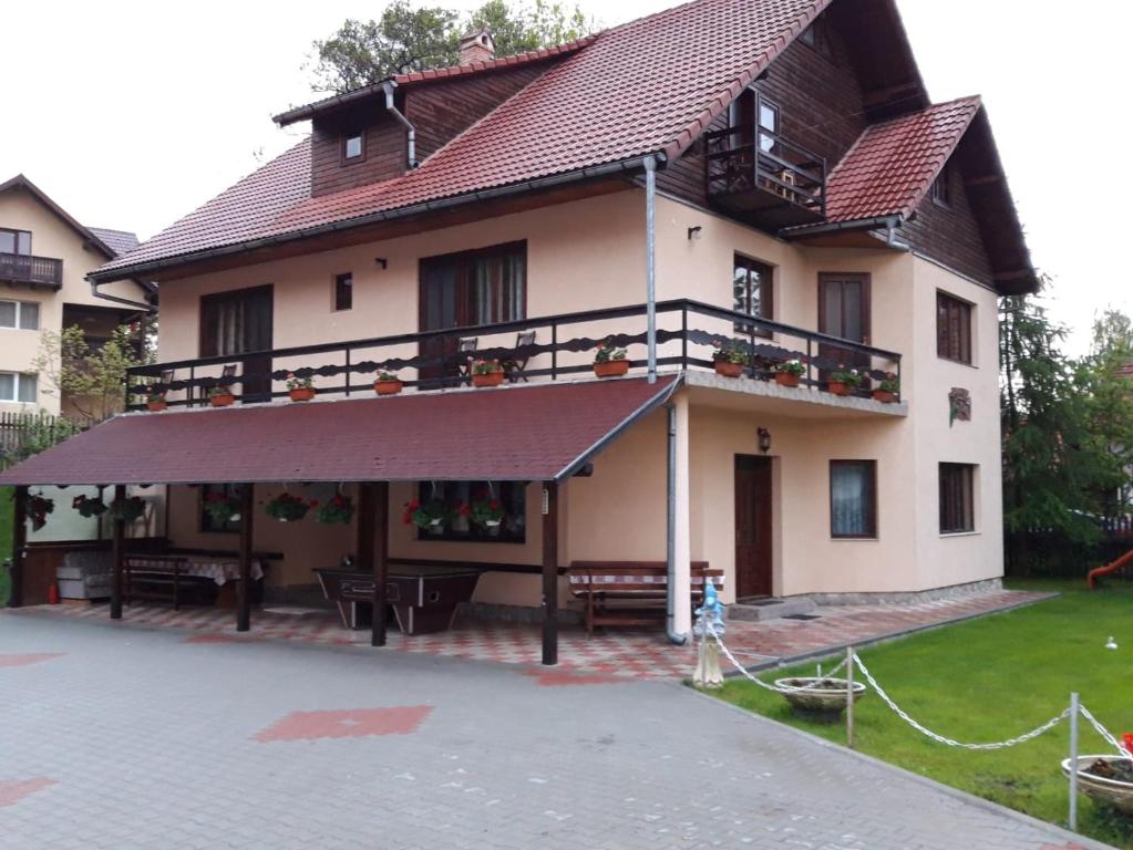 a large house with a balcony and a patio at Pensiunea Mariana in Bran