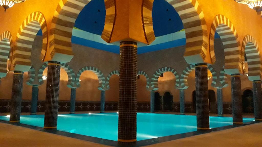 a swimming pool in a building with columns at Hotel Kasbah Azalay in Mhamid