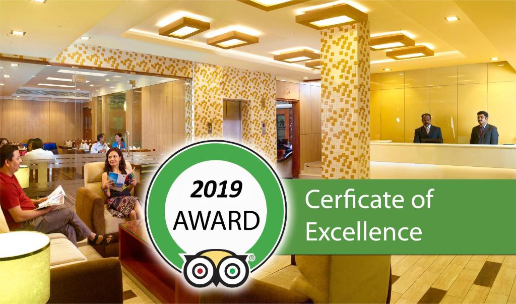 un logotipo de certificado de excelencia en un vestíbulo con personas sentadas en sillas en Hotel Aiswarya, en Kochi