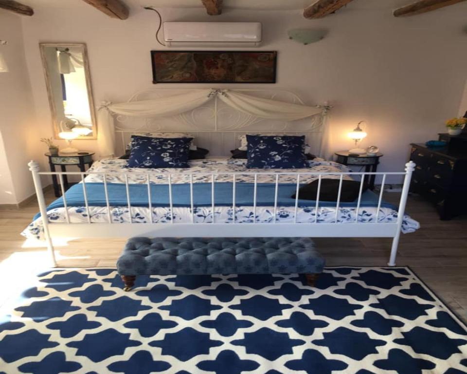 a bedroom with a white bed with a blue and white rug at Sunflower Guest House Bulgaria in Stefan Stambolovo