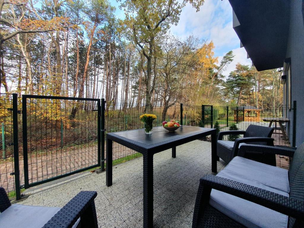 um pátio com uma mesa, cadeiras e uma cerca em DWIE SOSNY-Apartament na wydmie - 365PAM em Ustronie Morskie