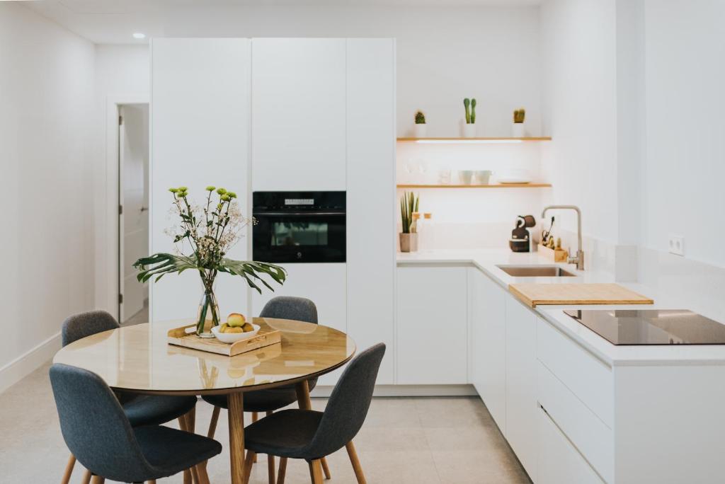 cocina blanca con mesa de madera y sillas en Céntrico estudio junto al Parque García Sanabria, en Santa Cruz de Tenerife