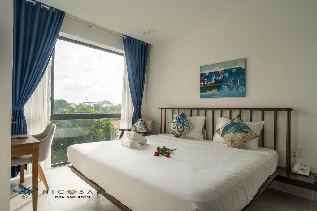 Schlafzimmer mit einem großen Bett und einem Fenster in der Unterkunft Nicobar Con Dao Hotel in Con Dao