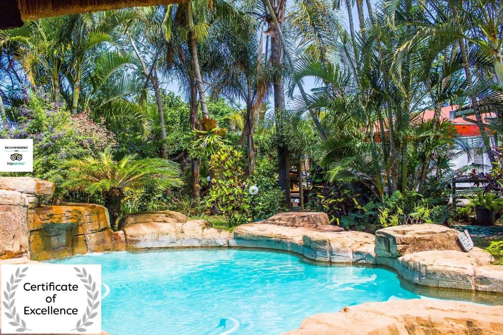 a large swimming pool in a garden with trees at Jessica's Self-catering in Durban
