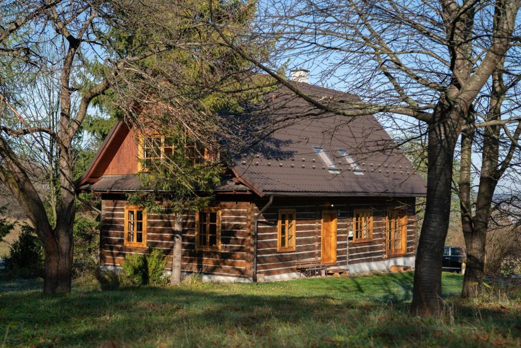 una cabaña de madera con árboles delante de ella en Pałacówka, en Dukla