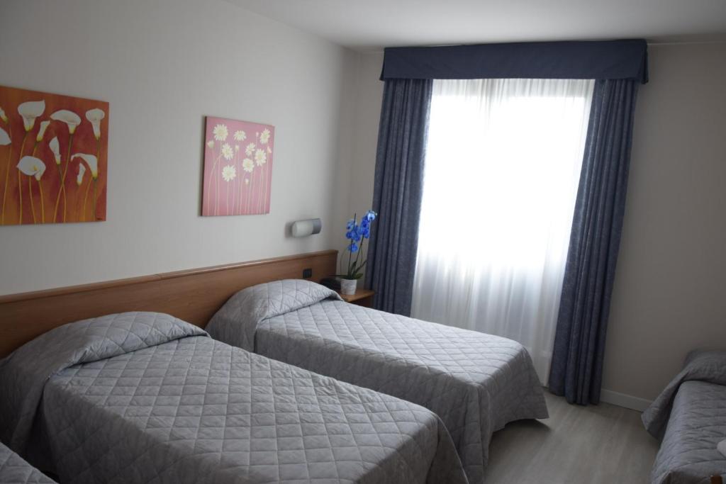 een slaapkamer met 2 bedden en een raam bij Hotel Gallia in Pianezza