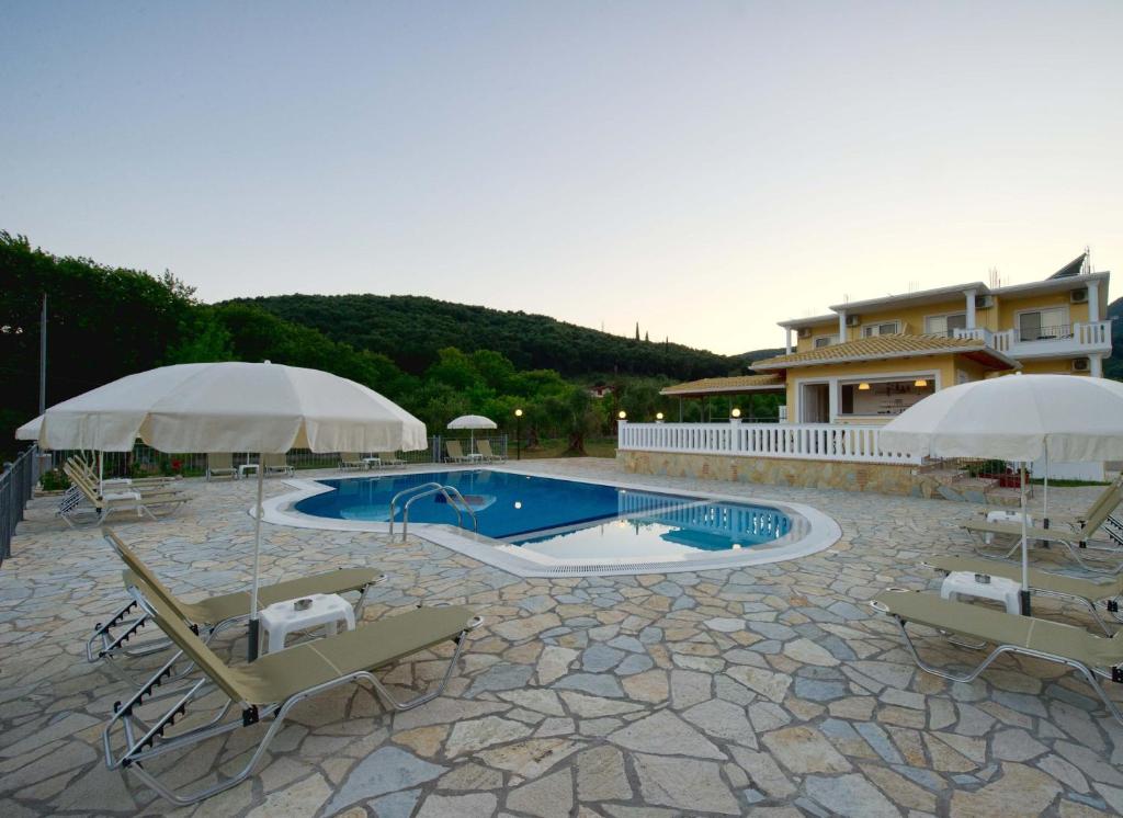 a pool with chairs and umbrellas next to a house at Alexander's House in Parga