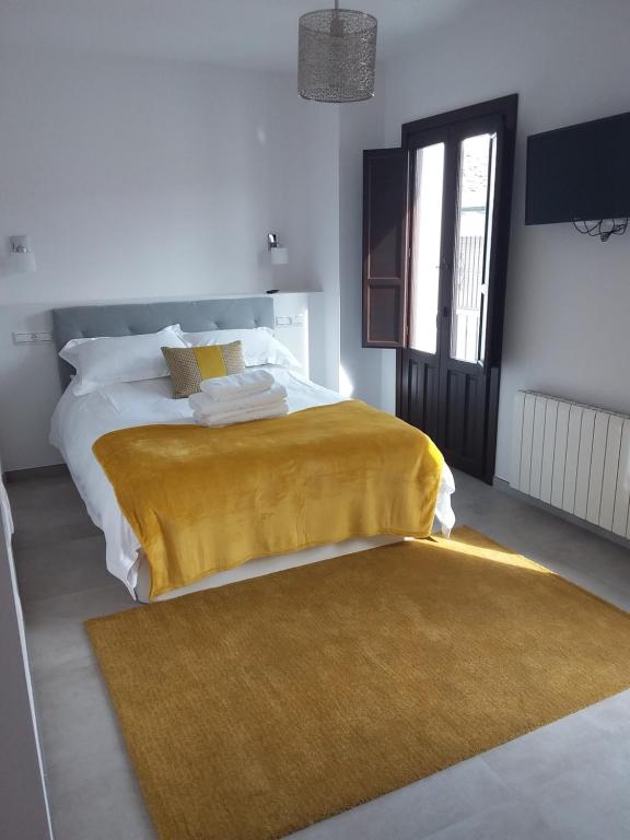 um quarto com uma cama com um cobertor amarelo em Casa Clavero em Ronda