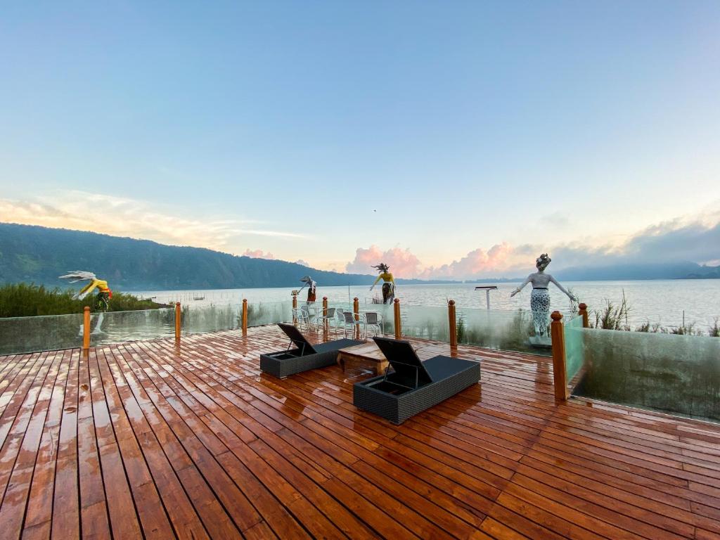 a wooden deck with a view of a body of water at Pondanu Cabins By The Lake in Bedugul