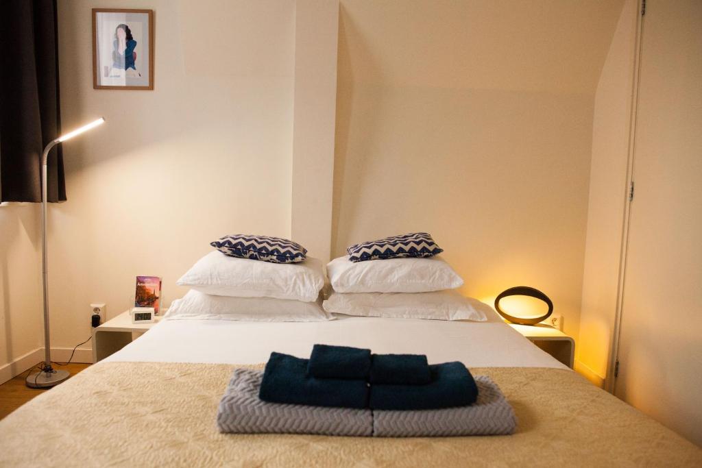 a bedroom with a white bed with blue and white pillows at Kuwadro Guesthouse Jordaan in Amsterdam