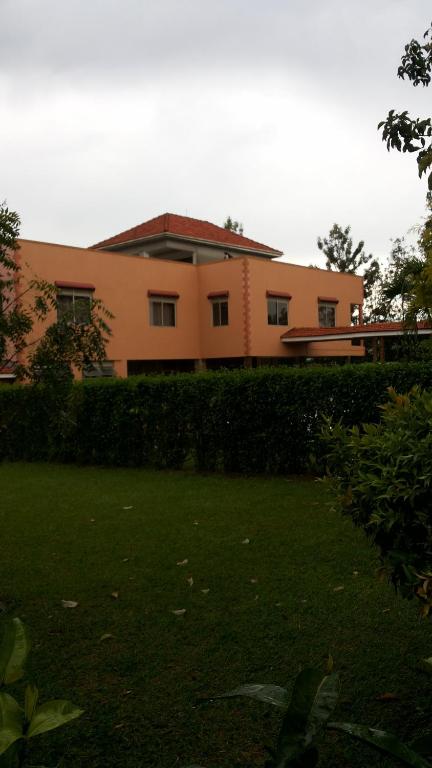 a house with a hedge in front of a yard at MakanHill Resort Hotel in Mityana