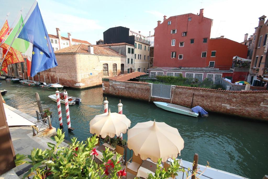 a view of a canal with two umbrellas and a boat at Ai Mori d&#39;Oriente in Venice