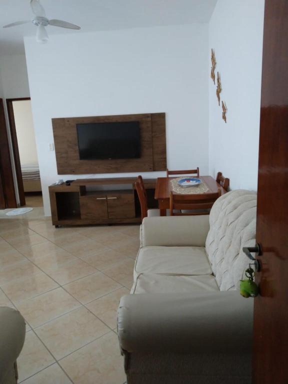 a living room with a couch and a flat screen tv at Apartamento em Bertioga sp in Bertioga