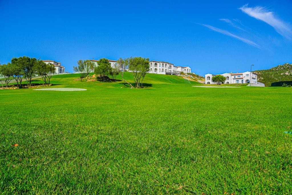 un grand champ vert d'herbe avec des maisons en arrière-plan dans l'établissement Geovillage Green Residence, à Olbia