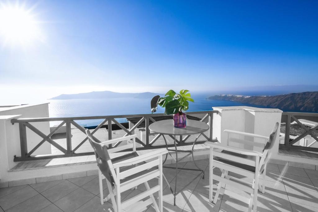 una mesa y sillas en un balcón con vistas al océano en Abelonas Retreat, en Imerovigli