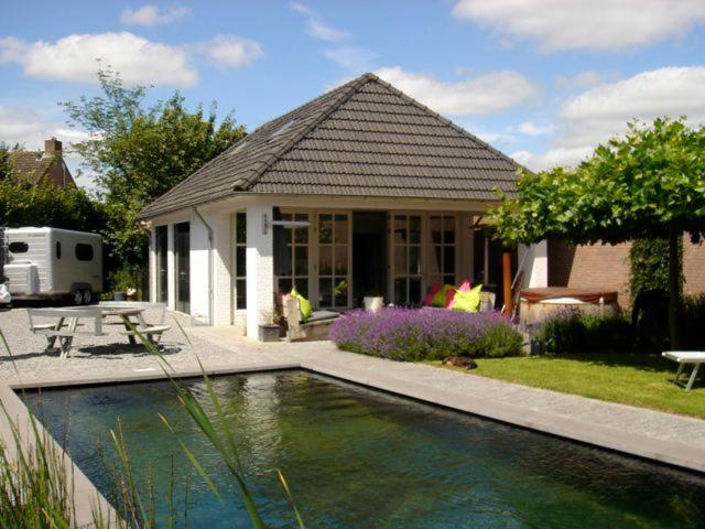 a house with a swimming pool in front of a house at Gardenhouse with private jacuzzi & private sauna in Teteringen